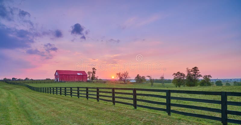 Classic red barn against a golden sunset sky